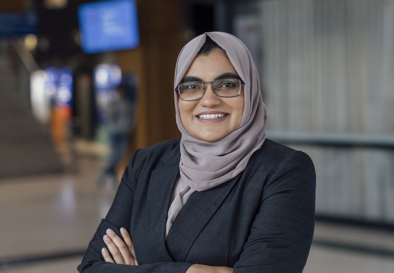 Image of a woman smiling while standing in the lobby of Melbourne Law School