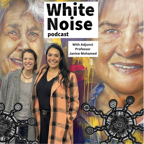 Two People stand in front of a wall with "White Noise Podcast with Adjunct Professor Janine Mohamed" written in a white box above their heads