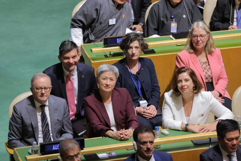 A high-angle group shot of Ambassador James Larsen alongside Prime Minister Anthony Albanese, Senator Penny Wong, and others at a table marked 