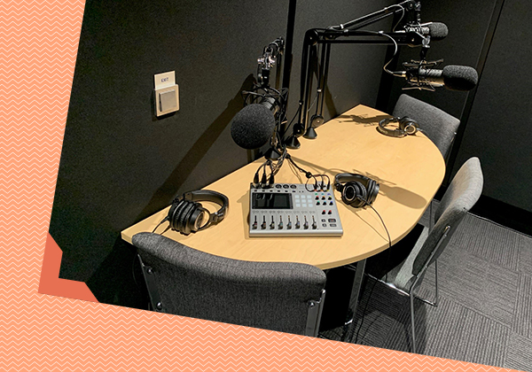This is a photo of podcast equipment at a table. It inclues microphones, chairs and a mixing board.
