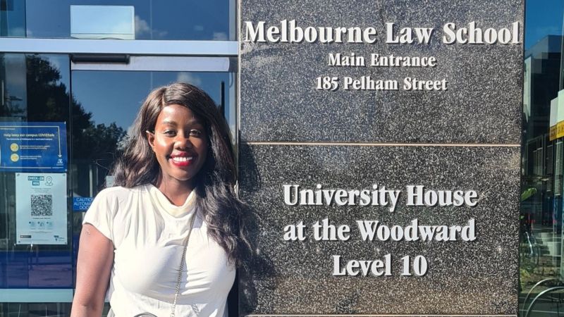 A woman stands in front of the Melbourne Law School building